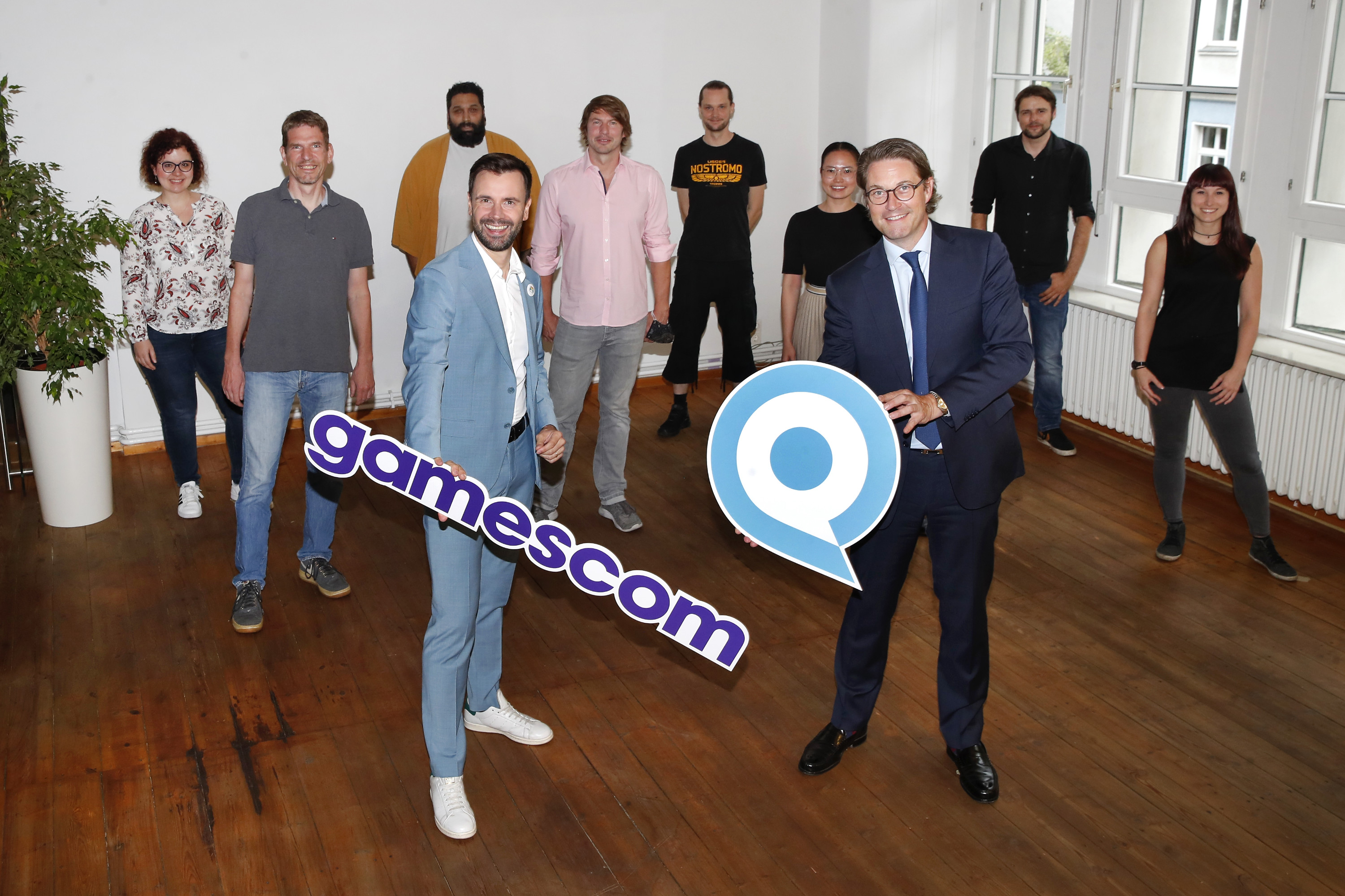 game-Geschäftsführer Felix Falk (vorne links mit gamescom-Schriftzug) und Bundesminister Andreas Scheuer mit Spiele-Entwicklerinnen und -Entwicklern beim Studio-Besuch von Yager (Franziska Krug/getty images)